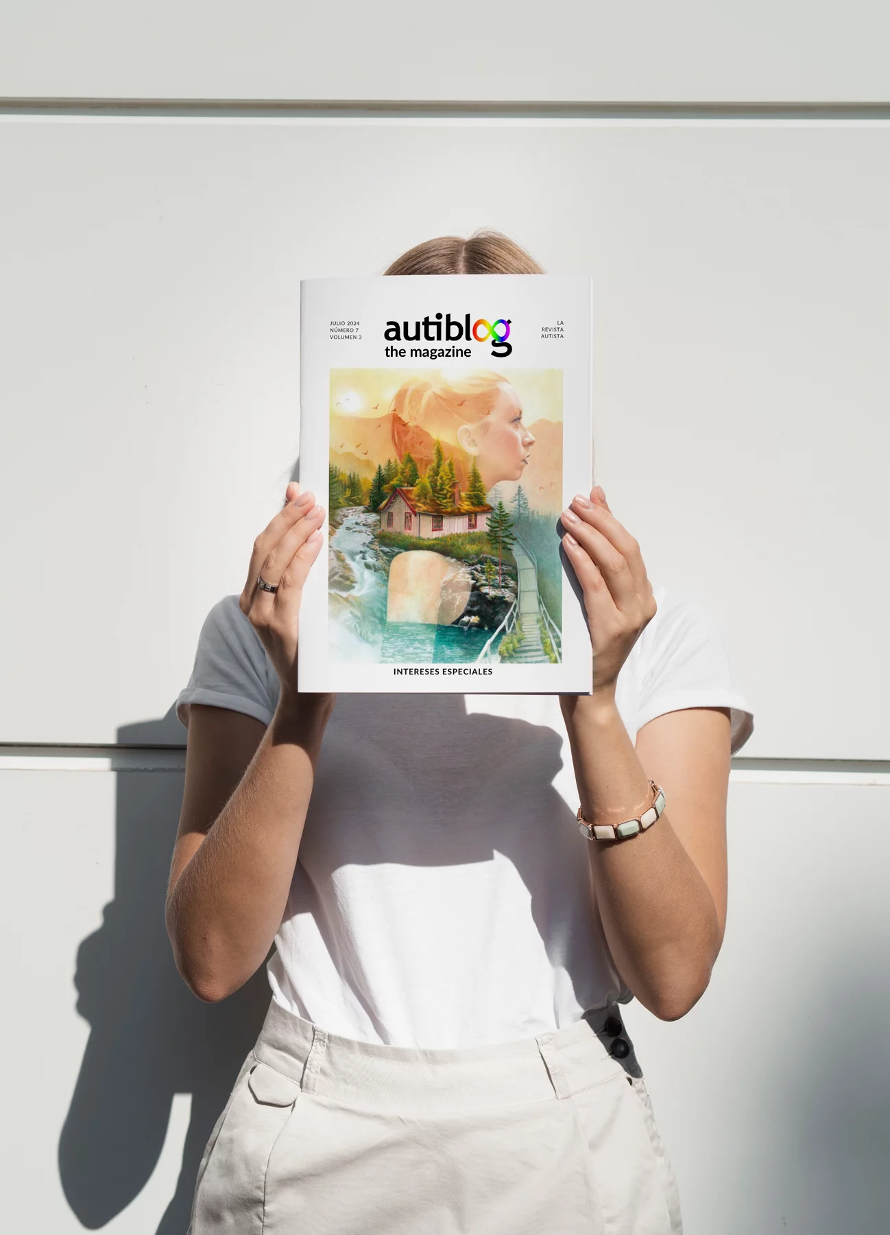 mujer se cubre la cara mostrando la portada de la revista Autiblog