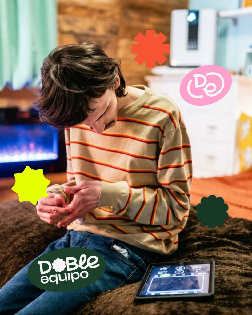Adolescente utilizando un comunicador dinámico mientras observa sus manos en un entorno doméstico.